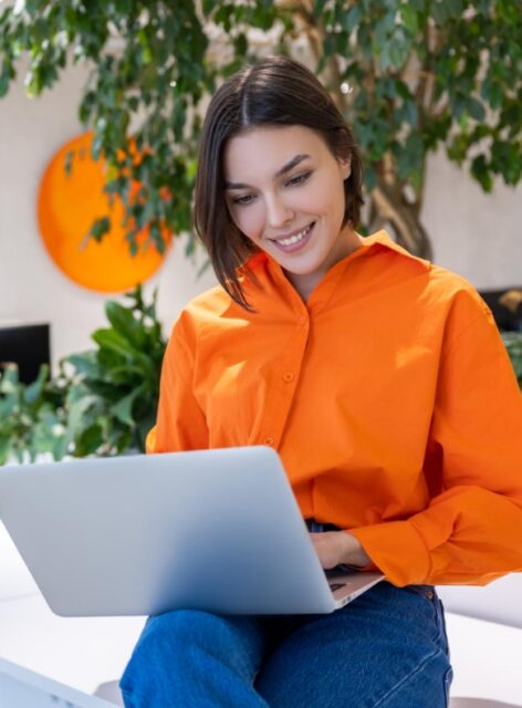 Woman sitting and smiling with a laptop.